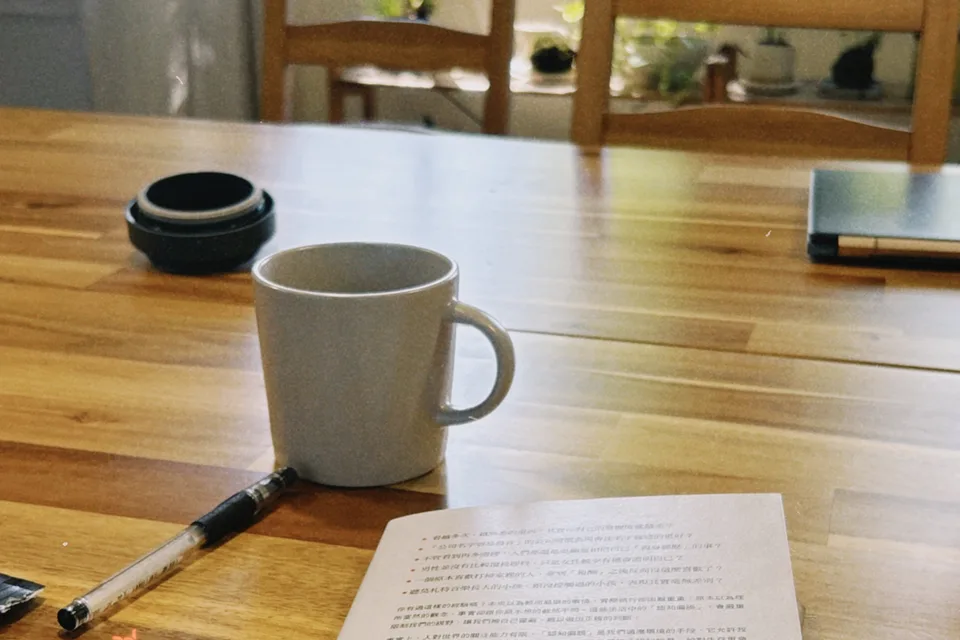 木桌上的書、筆與馬克杯